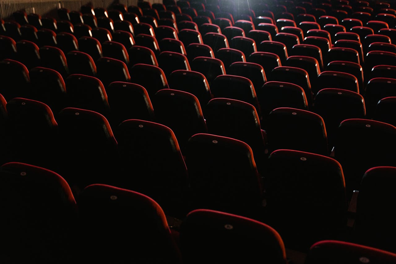 Fotografia das cadeiras de uma sala de cinema vazia.